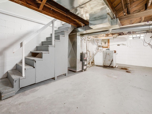 basement featuring stairway, washing machine and dryer, electric panel, and heating unit