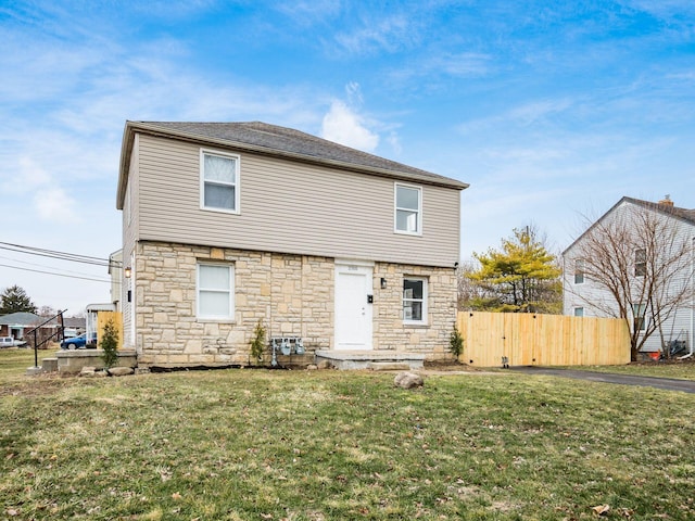 rear view of property with fence and a lawn