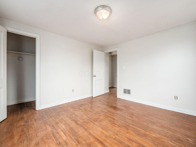 unfurnished bedroom with light wood finished floors, baseboards, visible vents, and a closet