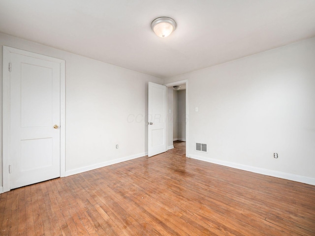 spare room featuring visible vents, light wood-style flooring, and baseboards