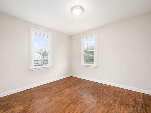 empty room with wood-type flooring and baseboards