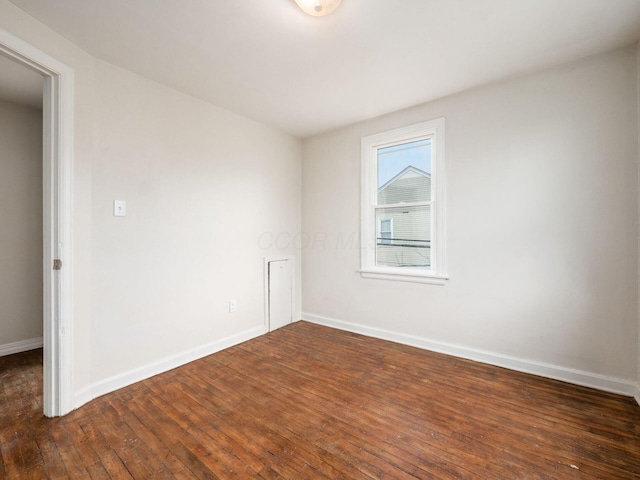 spare room with dark wood-style floors and baseboards