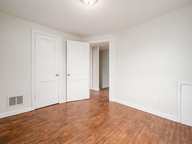 unfurnished bedroom featuring hardwood / wood-style floors, visible vents, and baseboards