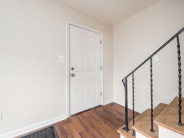 foyer with visible vents, stairway, baseboards, and wood finished floors