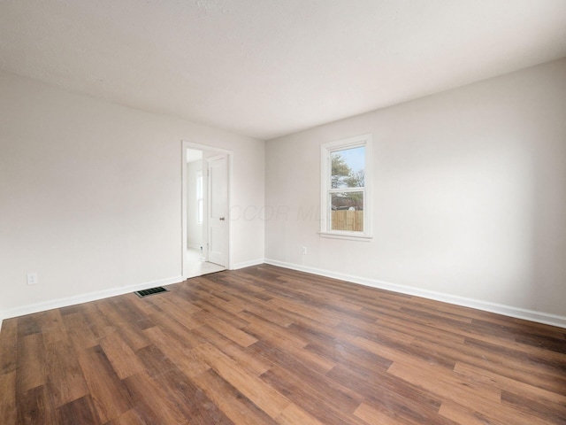 empty room featuring visible vents, baseboards, and wood finished floors