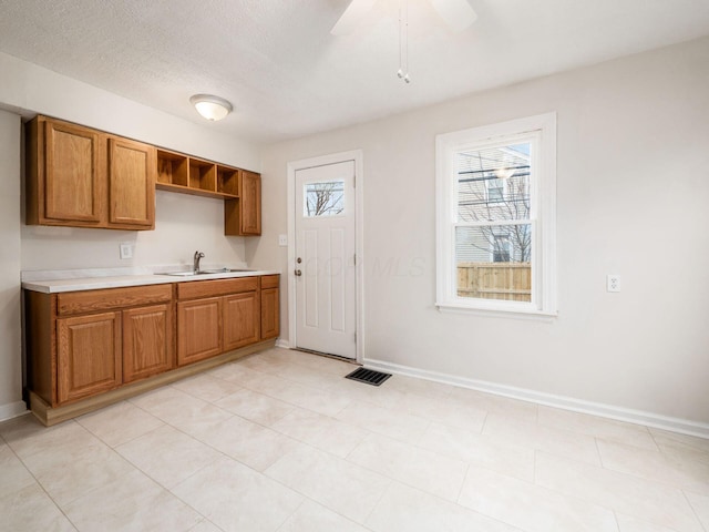 kitchen featuring brown cabinets, plenty of natural light, visible vents, and a sink