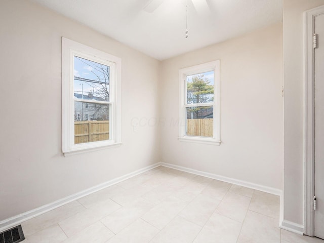 spare room with baseboards, visible vents, and ceiling fan