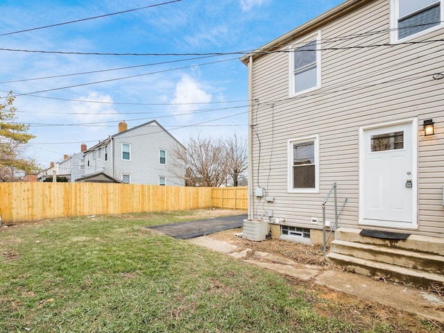 rear view of house with entry steps, a yard, central AC, and fence