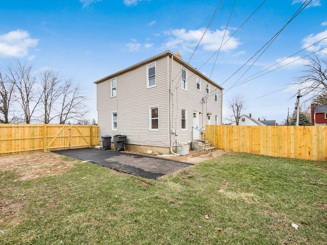 back of property with fence, aphalt driveway, a patio, and a yard