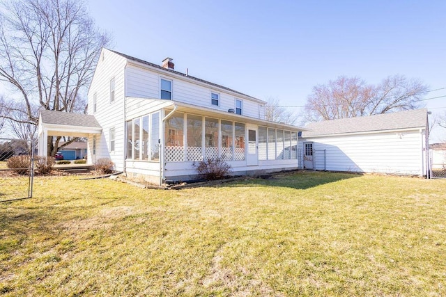 back of house with a yard, a chimney, a sunroom, fence, and a carport