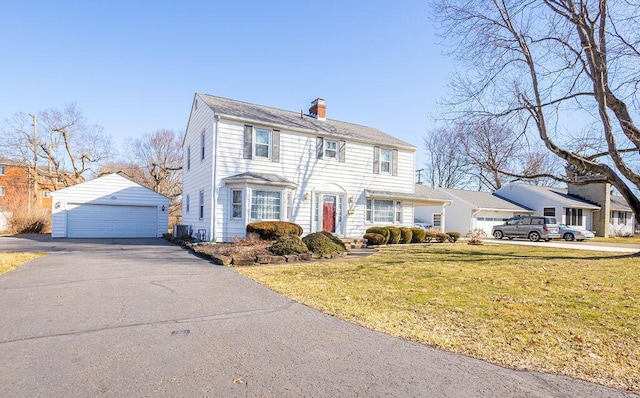 view of front of property with a garage, a front lawn, a chimney, and an outbuilding