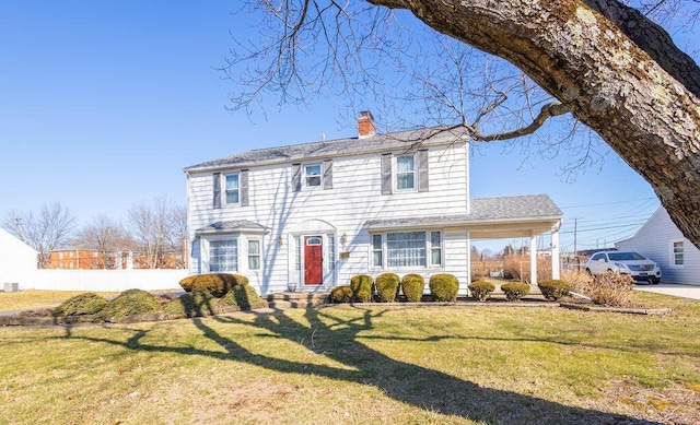 view of front of house featuring driveway, a chimney, a front lawn, and a carport