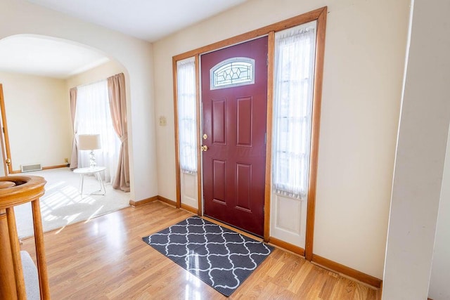 entryway with a wealth of natural light, arched walkways, and wood finished floors