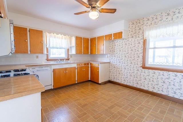 kitchen featuring dishwasher, light countertops, baseboards, and wallpapered walls