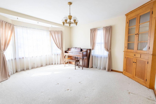 interior space featuring light carpet, an inviting chandelier, and baseboards