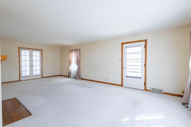 carpeted spare room with baseboards, visible vents, and french doors