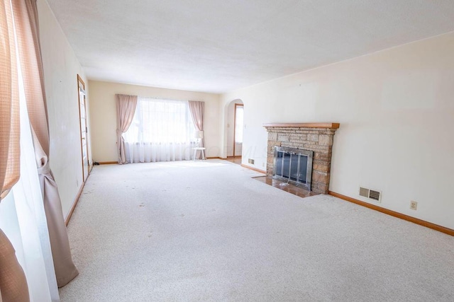 living room with carpet, arched walkways, visible vents, a fireplace with flush hearth, and baseboards