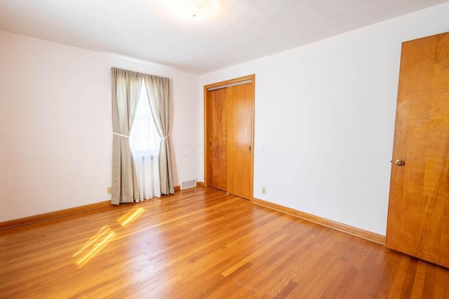 spare room with light wood-style floors, visible vents, and baseboards