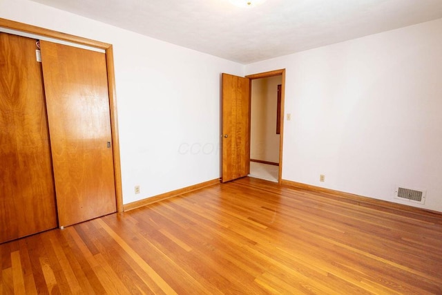 unfurnished bedroom with light wood-style floors, a closet, visible vents, and baseboards