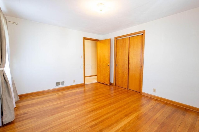 unfurnished bedroom with baseboards, a closet, visible vents, and light wood-style floors