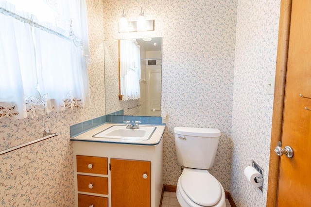 bathroom featuring vanity, toilet, and wallpapered walls