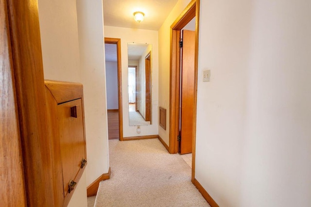 corridor with light carpet, baseboards, and visible vents