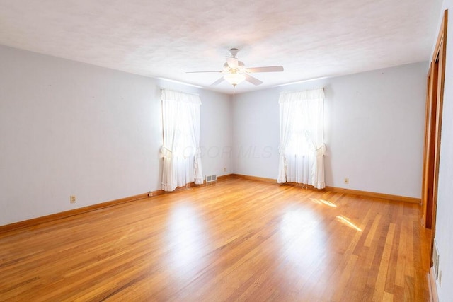 unfurnished room featuring baseboards, visible vents, a ceiling fan, a textured ceiling, and light wood-style floors