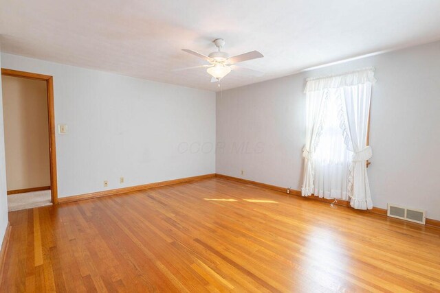 unfurnished room featuring light wood-style floors, baseboards, visible vents, and a ceiling fan