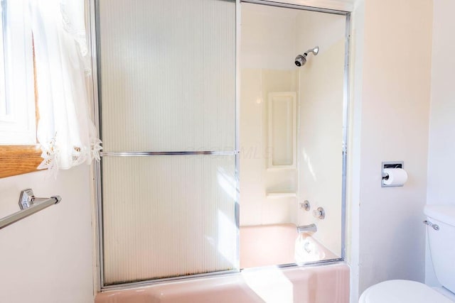 bathroom featuring bath / shower combo with glass door and toilet