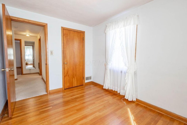 unfurnished bedroom with baseboards, multiple windows, and light wood-style floors