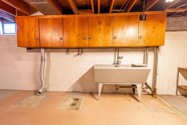 basement featuring concrete block wall and a sink