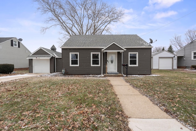 bungalow-style house featuring a garage, a shingled roof, a front yard, and an outdoor structure