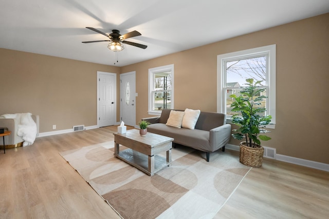 living room featuring visible vents, a ceiling fan, light wood-style flooring, and baseboards