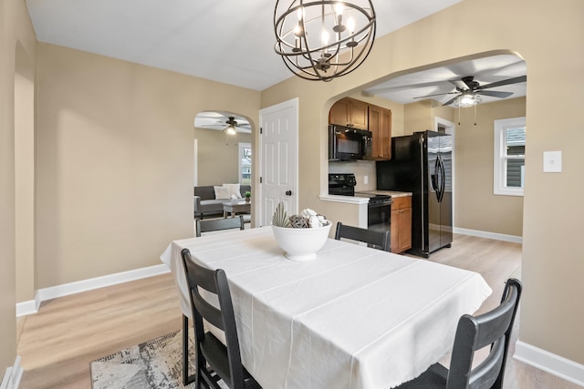 dining area featuring light wood-style floors, arched walkways, and baseboards