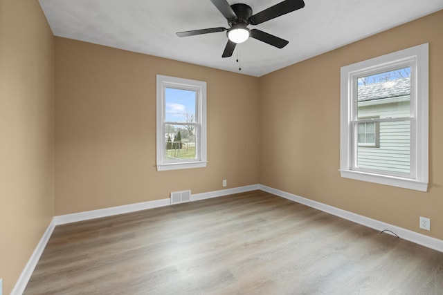 unfurnished room with light wood-type flooring, visible vents, and baseboards