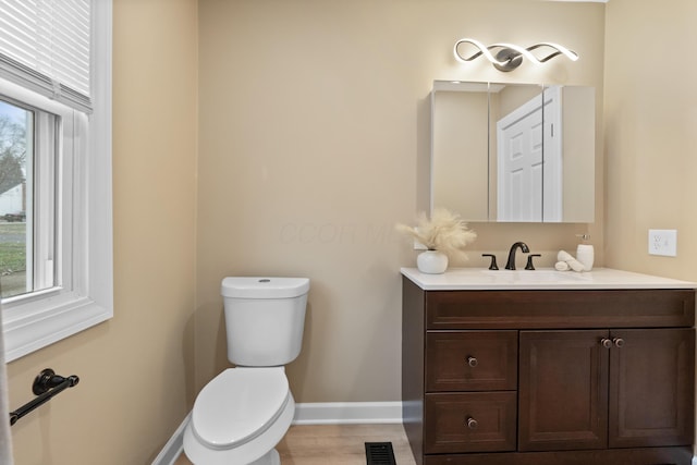 half bath with baseboards, visible vents, plenty of natural light, and toilet