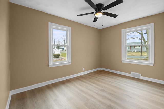 unfurnished room with baseboards, light wood-style floors, visible vents, and a healthy amount of sunlight