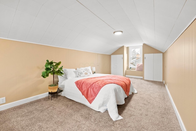 carpeted bedroom featuring lofted ceiling, wooden walls, and baseboards