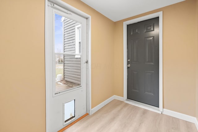 doorway to outside with light wood-style flooring and baseboards