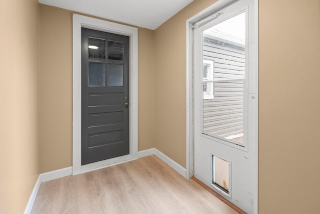 doorway featuring light wood-style flooring and baseboards