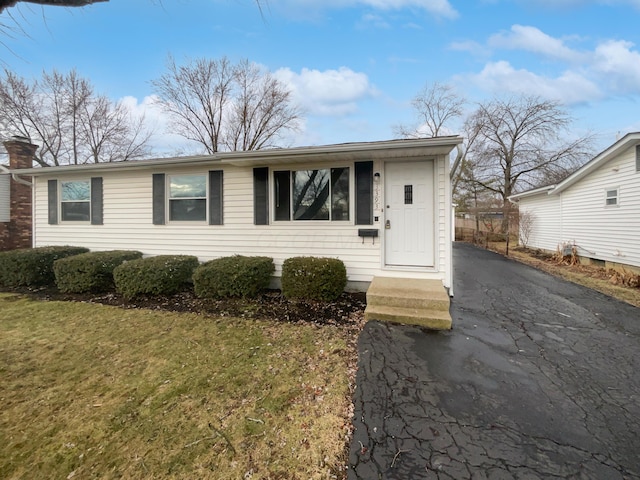 view of front of home featuring aphalt driveway, a front yard, and a chimney