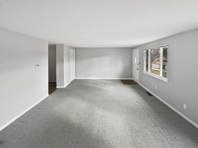 unfurnished room with carpet, visible vents, and baseboards