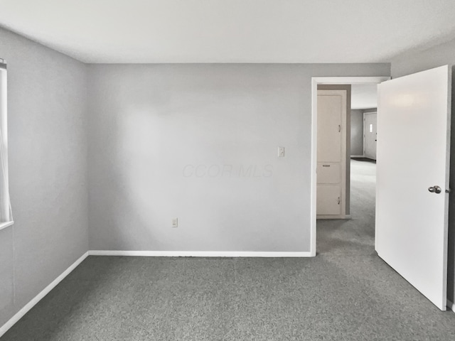 empty room featuring carpet and baseboards