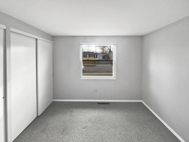 unfurnished bedroom featuring carpet, visible vents, baseboards, and a closet