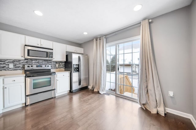 kitchen featuring light countertops, appliances with stainless steel finishes, dark wood-style flooring, and decorative backsplash