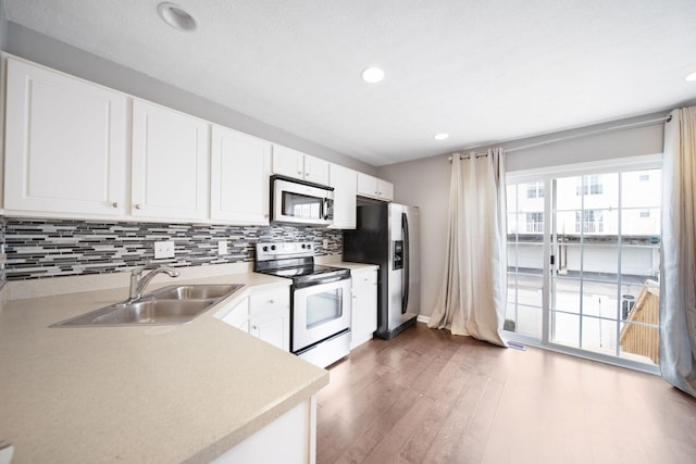 kitchen with stainless steel appliances, wood finished floors, a sink, light countertops, and backsplash