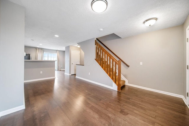 unfurnished living room with baseboards, stairway, and wood finished floors