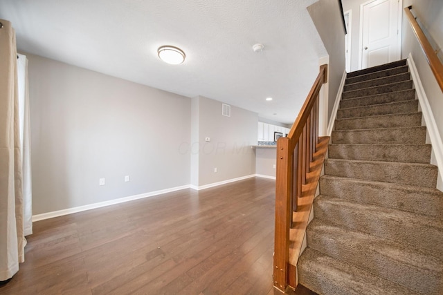 stairway with recessed lighting, visible vents, baseboards, and wood finished floors