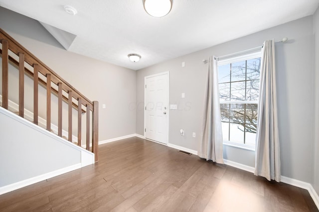 entrance foyer with dark wood-style floors, visible vents, baseboards, and stairs