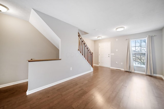 empty room featuring stairway, baseboards, and wood finished floors